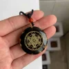 Pendentif orgonite Métatron noir et or tenu dans la main