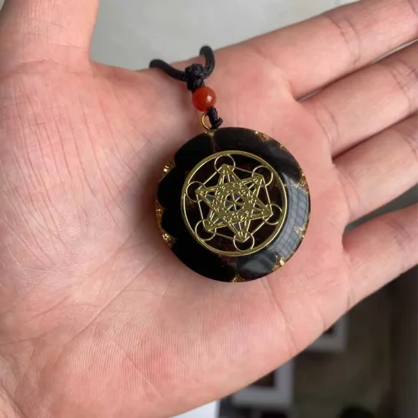 Médaillon orgonite noir et or de 3,5 cm dans la main